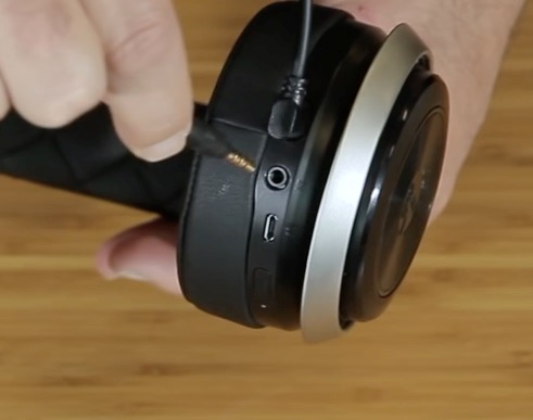 Image showing someone plugging in the 3.5mm chat cable into the bottom of the headphones