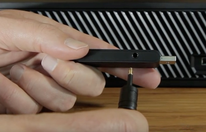 Image of someone plugging in the 3.5mm headphone jack on the end of the optical cable to the base station for the LS30/LS31 headphones
